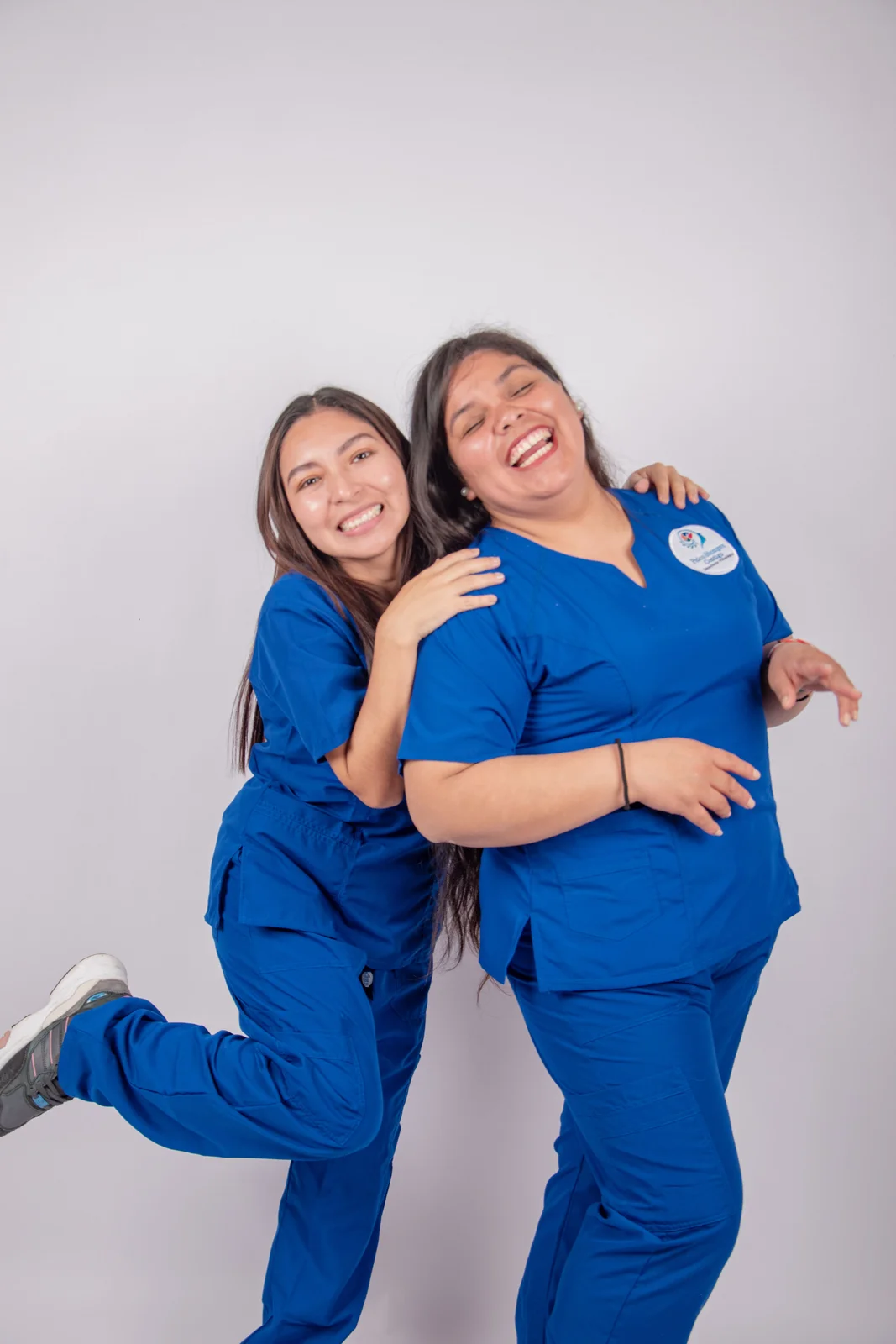 Twee verpleegkundigen in dienstkleding lachen samen